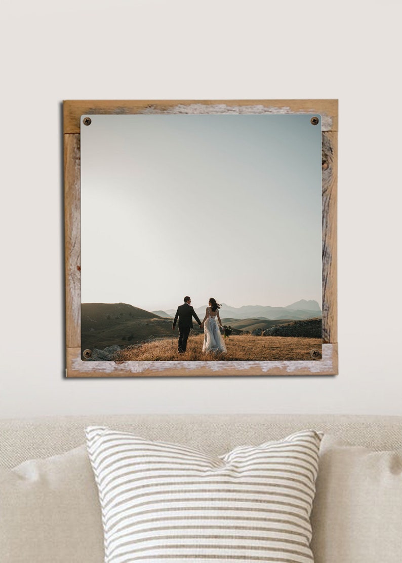 May include: A framed photograph of a couple walking away from the camera on a grassy hilltop. The couple is wearing wedding attire and the background is a mountain range with a cloudy sky.