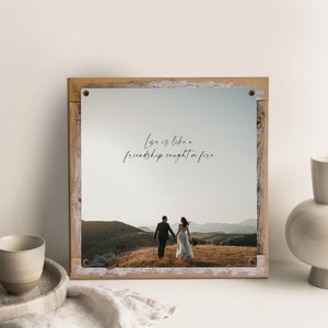 May include: A rustic wooden framed print with a quote that reads "Love is like a friendship caught on fire." The print features a photograph of a couple walking away from the camera in a field.