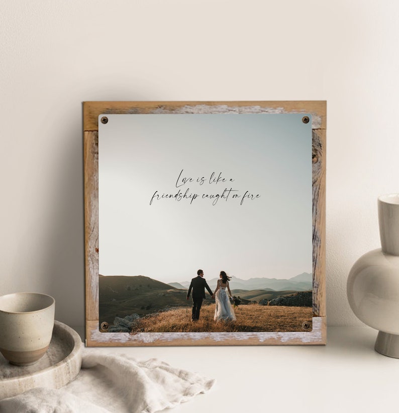 May include: A rustic wooden framed print with a quote that reads "Love is like a friendship caught on fire." The print features a photograph of a couple walking away from the camera in a field.
