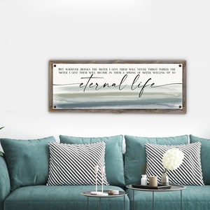 May include: A wooden sign with a watercolor background in shades of blue and gray. The sign features a quote about eternal life: "But whoever drinks the water I give them will never thirst. Indeed the water I give them will become in them a spring of water welling up to eternal life."