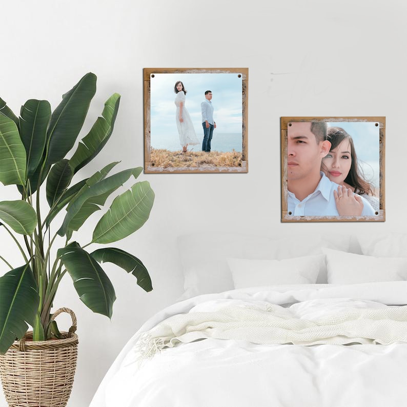 May include: Two framed photographs of a couple. The first photo shows the couple standing on a grassy hill, looking out at the ocean. The second photo shows the couple looking at the camera, with the woman resting her head on the man's shoulder.