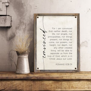 May include: A rustic wooden framed sign with a white background and black text. The text reads "For I am convinced that neither death, nor life, nor angels, nor principalities, nor things present, nor things to come, nor powers, nor height, nor depth, nor any other created thing, will be able to separate us from the love of God, which is in Christ Jesus our Lord. Romans 8:38-39".