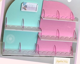 May include: A digital file for a shelf display with two sections, one light blue and one pink. The shelves have scalloped edges and pink acrylic dividers. The file includes a digital download for a shelf display.