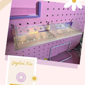 Può includere: Una lavagna forata rosa con un ripiano e divisori in acrilico trasparente. Il ripiano ha un bordo smerlato. L'immagine include anche il testo "Digital File" e il sito web "glopezcreations.com".