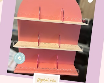 May include: A three-tiered pink shelf display with scalloped edges and clear acrylic dividers. The shelf is designed for displaying small items, such as jewelry or cosmetics. The digital file is for creating a shelf display.