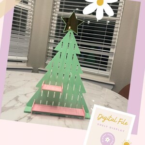 May include: A green and pink Christmas tree shelf display with a gold star on top. The text "Digital File Shelf Display" is on a white background with a pink and yellow sun.