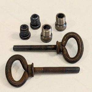 May include: Two rusty metal hooks with a heart-shaped loop on one end and a threaded screw on the other. Four small metal caps are also included.