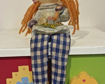 Figura de resina de niña de jardín con cabello rojo y pantalones a cuadros azules.