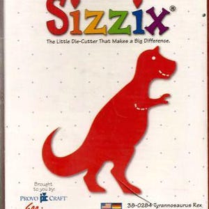 May include: A red Tyrannosaurus Rex die-cut from Sizzix. The packaging features the Sizzix logo in rainbow colours, the text "The Little Die-Cutter That Makes a Big Difference," and the Provo Craft and Ellison logos. The product number is 38-0284.