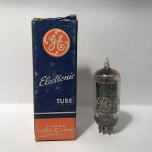 May include: A vintage General Electric electronic tube and its original box. The box is navy blue with a GE logo and the words "Electronic TUBE". The tube is clear glass with internal components and a GE logo.