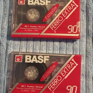May include: Two BASF Ferro Extra I 90 audio cassette tapes in clear plastic cases with red and white labels. The labels feature the text BASF, Ferro Extra I, 90, Extraslim, IEC I Position: Normal, Precision Cassette Mechanism, and 2x45min 135m.