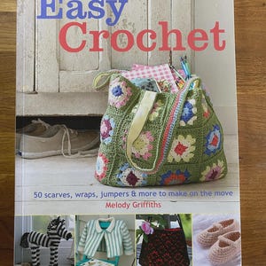 Könnte beinhalten: Das Buch "Easy Crochet" mit einer grünen gehäkelten Tragetasche. Der Titel des Buches ist in Blau und Rot gehalten. Darunter befinden sich Bilder von Häkelprojekten, darunter ein Zebra, eine Jacke, eine Tasche und Hausschuhe.