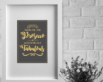 May include: A framed print with a black background and gold lettering that reads "Darling, hand me the Prosecco & watch me get fabulous".