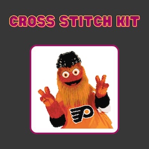 Op de afbeelding: Cross-stitch set met een cartoon mascotte met oranje vacht, een zwart-wit shirt met het logo van de Philadelphia Flyers en een zwart-witte pet. De mascotte maakt een peace-teken met beide handen.
