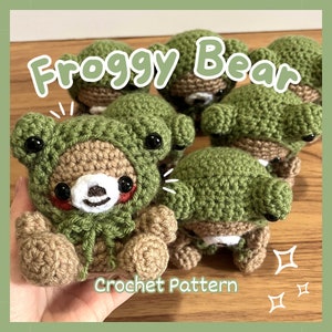 Puede incluir: Varios peluches de crochet Frogggy Bear. Cada oso es marrón con una capucha verde con forma de rana, ojos negros y un hocico blanco. El texto "Froggy Bear" y "Crochet Pattern" son visibles.