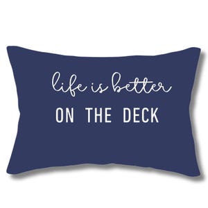 May include: A navy blue throw pillow with white text that reads "life is better on the deck".