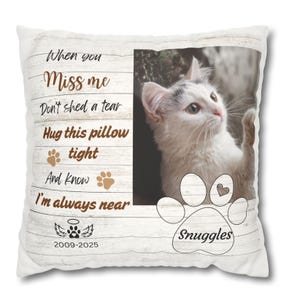 May include: White decorative pillow with a photo of a white and gray cat. Text on the pillow reads "When you miss me, don't shed a tear, hug this pillow tight, and know I'm always near." Includes a paw print and the word "Snuggles".