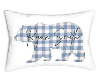 Può includere: Cuscino rettangolare bianco con una silhouette di orso a quadretti blu e bianchi. La forma dell'orso è riempita con un motivo a scacchi blu e bianco. Il nome "Ryan Smith" è scritto sull'orso in corsivo.
