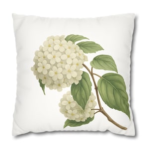 May include: White square throw pillow featuring a botanical illustration of a hydrangea plant. The artwork depicts clusters of white flowers, green leaves, and a brown stem against a white background. The pillow has a soft, inviting appearance.