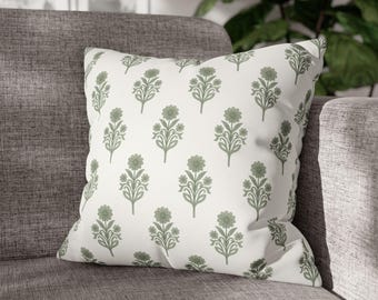 May include: Square cushion featuring a white backdrop adorned with a repeating pattern of sage green floral motifs. The cushion is placed on a grey sofa, providing a decorative element for home interiors.