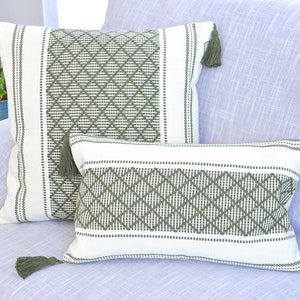 May include: Two decorative throw pillows with a white background and green diamond pattern. The pillows have green tassels on the corners.