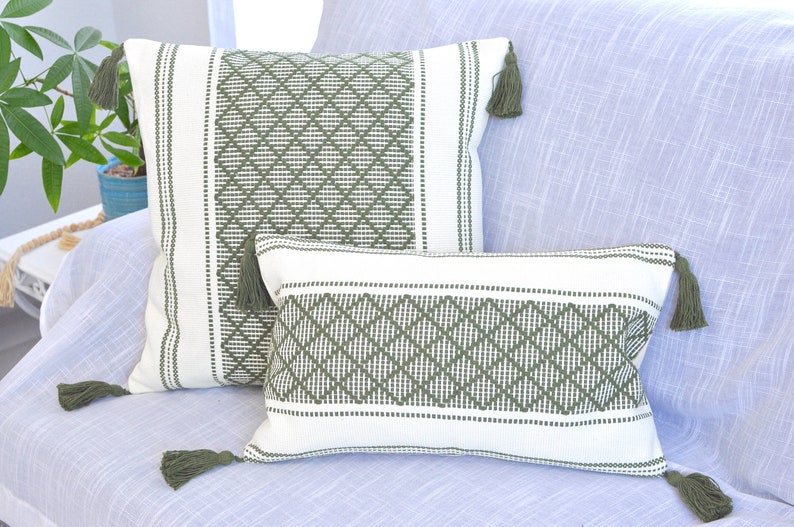May include: Two decorative throw pillows with a white background and green diamond pattern. The pillows have green tassels on the corners.