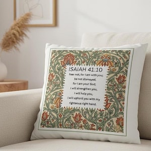 May include: White square throw pillow with a floral design in orange, green, and cream. The pillow features the text "ISAIAH 41:10" and a Bible verse. The pillow is placed on a beige sofa.