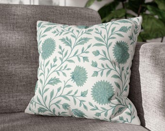 May include: A white cushion with a green floral pattern. The cushion features a repeating design of green leaves and flowers.