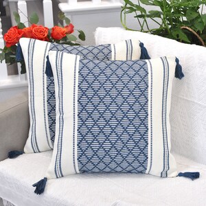 May include: Two blue and white patterned throw pillows with tassels. The pillows have a geometric design with white stripes and blue diamond patterns.
