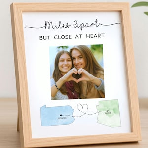 May include: A framed photo with the text "Miles apart BUT CLOSE AT HEART." The photo shows two women making a heart shape with their hands. Below, state maps connect with a dotted line, labeled "Jessica" and "Alice."