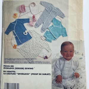 May include: A sewing pattern for baby clothes with a focus on overlock stitching. The pattern includes a kimono, pyjamas, and a bib. The image also features a baby wearing a striped onesie.