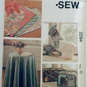 Puede incluir: Patrón de costura para accesorios de cocina, que incluye un mantel, guantes para horno y una cubierta para caja de pan. El patrón es para un diseño a cuadros con acentos florales. El número de patrón es 2284.