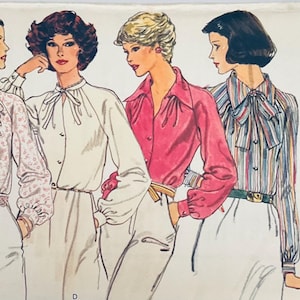 May include: A Very Easy Vogue Patterns sewing pattern envelope 9816 featuring illustrations of four blouses with long sleeves, button fronts, and tie-neck details. The designs include a floral print, a solid white, a solid pink, and a multi-colored stripe.