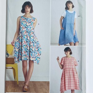 Pode incluir: Imagem de um padrão de costura com três designs de vestidos diferentes. Um é sem mangas com uma estampa floral colorida, outro é um vestido azul e o terceiro é um vestido xadrez vermelho e branco com mangas curtas.