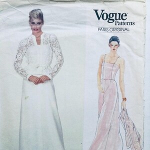 May include: Vogue Patterns Paris Original sewing pattern featuring two women's dress designs. The first dress is a white lace top with a long white skirt. The second dress is a pink sleeveless dress with a matching pink scarf.