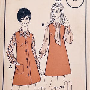Puede incluir: Patrón de costura vintage con dos diseños de vestidos. Uno tiene botones y un bolsillo, el otro un cuello con lazo. Las ilustraciones son de estilo retro, con la talla 36 impresa en la parte superior.