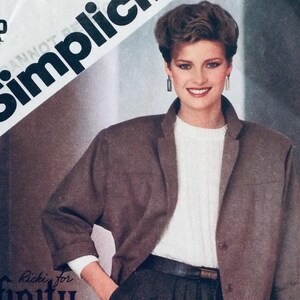 Può includere: Un blazer marrone con un maglione bianco e una cintura nera. La modella indossa un maglione bianco con un blazer marrone e una cintura nera. Il blazer ha un colletto a revers e una chiusura con un solo bottone. Il maglione è uno stile semplice a collo rotondo. La cintura è una semplice cintura in pelle nera con una fibbia argentata.