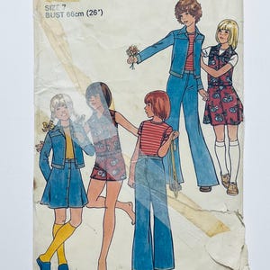 Puede incluir: Un patrón de costura vintage para ropa de niñas, con cuatro atuendos diferentes. El patrón incluye una chaqueta vaquera, una falda vaquera, un pantalón vaquero, un vestido sin mangas y una camiseta a rayas. El patrón es para la talla 7, con una medida de pecho de 66 cm (26 pulgadas).