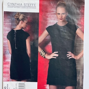 Puede incluir: Patrón de costura Vogue Patterns de Cynthia Steffe. El patrón presenta un vestido negro con cremallera en la espalda. La imagen incluye una foto de un modelo con el vestido. El texto "Vogue Patterns American Designer" es visible.