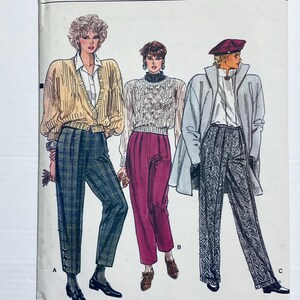Könnte beinhalten: Illustration von drei Damenmode-Ensembles. Das erste zeigt eine gelbe Strickjacke, ein weißes Hemd und eine karierte Hose. Das zweite hat einen Zopfstrickpullover und eine bordeauxfarbene Hose. Das dritte Outfit umfasst einen grauen Mantel, eine gemusterte Hose und eine Baskenmütze.