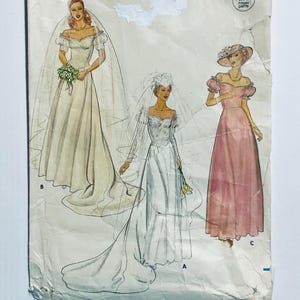 May include: A vintage sewing pattern with illustrations of three elegant gowns. The designs include a wedding dress with a veil and bouquet, a long-sleeved bridal gown with a train, and a pink formal dress with a hat.