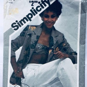 Puede incluir: Un patrón de costura Simplicity que muestra a una mujer con una chaqueta gris con estampado floral, un top blanco de bandeau y pantalones blancos. El número del patrón es 1178.