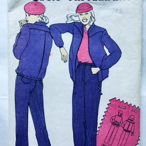 Op de afbeelding: Een vintage naaipatroon voor een jas- en broekset. Het patroon toont twee vrouwen die de outfit dragen, een met een roze hoed en de andere met een blauwe hoed. Het patroon is gemarkeerd met "70's".