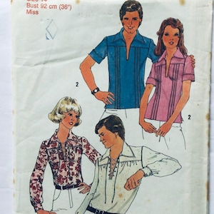 May include: A sewing pattern for a shirt with a 92 cm bust. The pattern includes instructions for making a blue shirt with a collar and a pink shirt with a collar. The pattern also includes instructions for making a white shirt with a lace-up front.