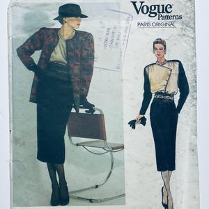 May include: A Vogue Patterns Paris Original sewing pattern envelope featuring illustrations of a two-piece outfit consisting of a long-sleeved jacket with a red and black patterned design, a light-colored top, and a solid black knee-length skirt.