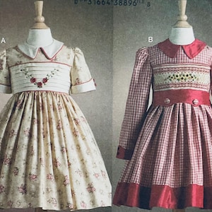 May include: Two vintage-style dresses on mannequins. One is cream-colored with a floral pattern and red accents. The other is red and white gingham with red trim. Both dresses have detailed bodices and collars, showcasing a classic design.