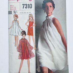 Może przedstawiać: Koperta z wykrojem krawieckim vintage o numerze 7310 dla rozmiaru 14, biust 34. Okładka zawiera ilustracje trzech różnych stylów sukienek, w tym białej sukienki z dekoltem typu halter, czerwonej sukienki etui oraz czerwonej sukienki z koronkową narzutką.