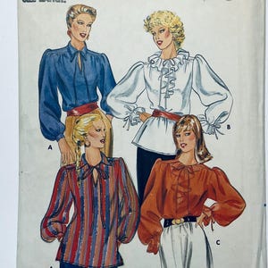 Peut inclure: Une pochette de patron de couture vintage illustrant quatre modèles de chemisiers différents à manches longues, avec des détails de col à nouer et des volants. Les modèles incluent un chemisier bleu uni, un chemisier blanc à volants, un chemisier rayé et un chemisier rouille.