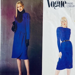 Pode incluir: Um padrão de costura vintage Vogue Paris Original com duas ilustrações de mulheres vestindo vestidos azuis. O padrão é para um vestido com um corpete ajustado e uma saia que cai até o joelho. O vestido é mostrado com um cinto e uma gola.
