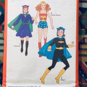 Può includere: Modello di cucito vintage con tre costumi di supereroi per bambini: Catwoman, Batgirl e Wonder Woman. Il modello include istruzioni e illustrazioni per ogni costume.